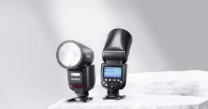 Two Godox V1Pro flashes sit on a white rock in front of a gray background.