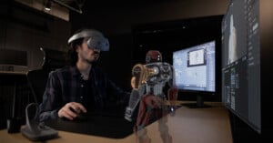 A man uses the Sony XR HMD to design a 3D character in front of his computer.